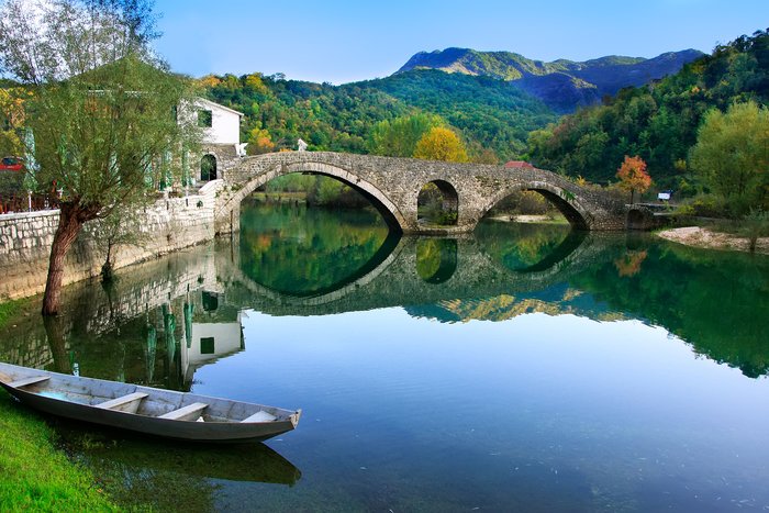 A stone-arched bridge reflected in the Crnojevića river in Montenegro