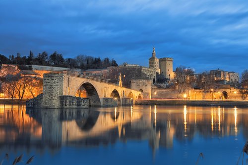 Historic Avignon's Palais des Papes and Pont Saint-Bénézet glow serenely in the early evening