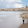 A woman walks the empty beach of Cefalu in the winter. 