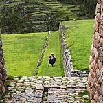 Peruvian woman walking through the Inca ruins of Chinchero