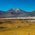 Panoramic view of Andean peaks and a mineral-rich lagoon in the Atacama region