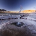 Steaming Tatio geysers erupting on a geothermal field 