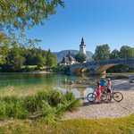 A cycling family enjoys the view of Bohinj Lake.