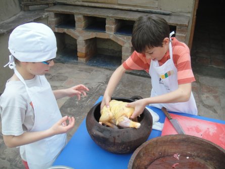 Kids baking a chicken according to a traditional Peruvian recipe