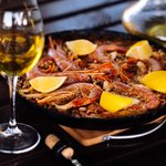 A plate of seafood paella and glass of wine