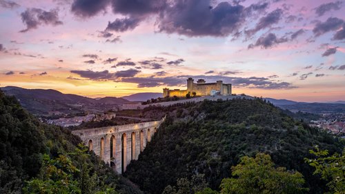 Spoleto at sunset, with the medieval bridge of Ponte delle Torri and Rocca Albornoziana hilltop fortress