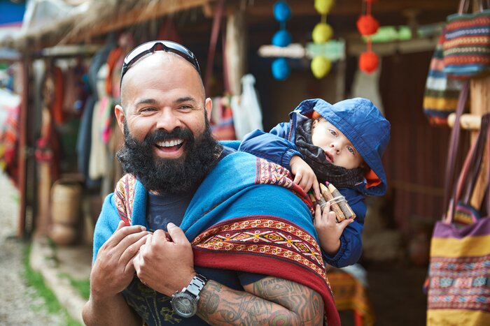 A man carrying his child through a market in Peru
