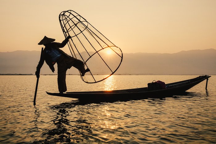 Intha man using the unique methods of rowing and catching fish on Inle Lake (Shan State).