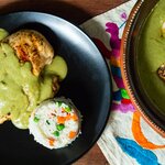 Black plates, holding traditional Oaxacan green mole, sit on colorful place mats