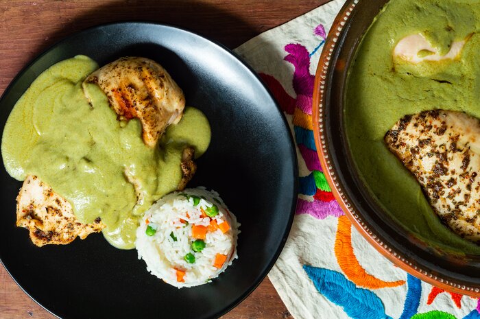 Black plates, holding traditional Oaxacan green mole, sit on colorful place mats