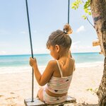 Child playing on a swing on a beach in Lombok
