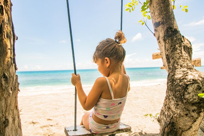 Child playing on a swing on a beach in Lombok
