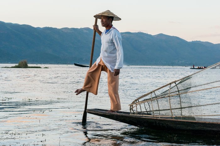 Horizontal picture of burmese fishermen posing with paddle during sunset at Inle Lake, Myanmar.