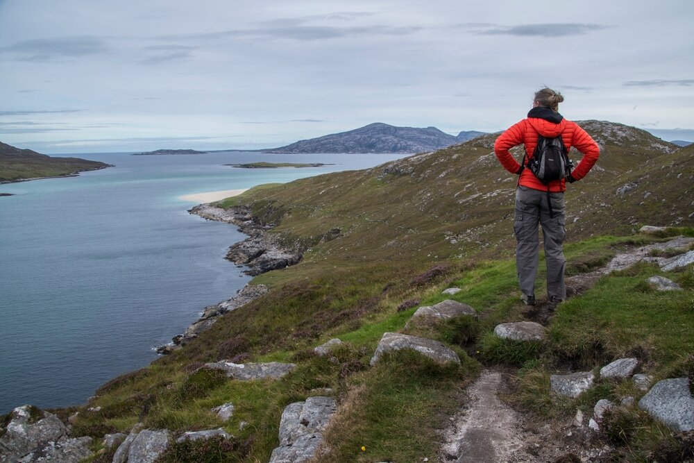 A woman enjoys the views of Scarp and nearby beach in Hushinish on Lewis in the Outer Hebrides in Scotland