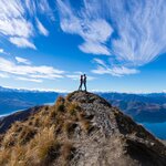 A young couple stands atop Roy's Peak between Wānaka and Glendhu Bay