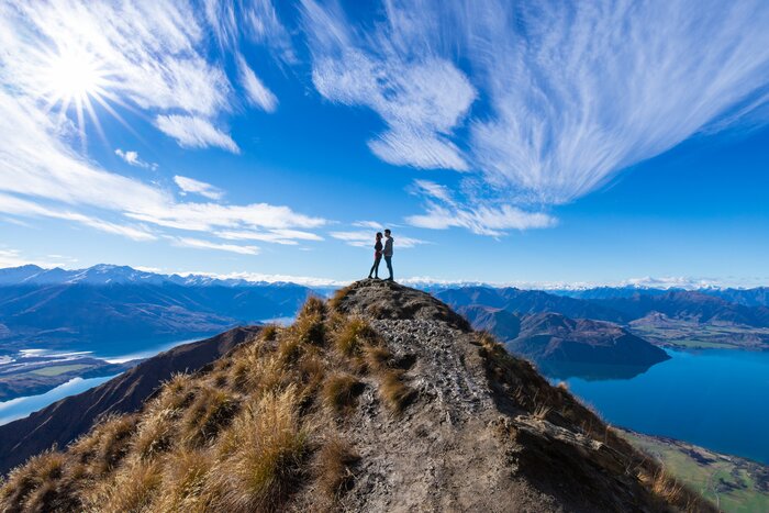 A young couple stands atop Roy's Peak between Wānaka and Glendhu Bay