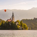  Hot air balloon flies over Lake Bled, Pilgrimage church, and Bled Castle in the background