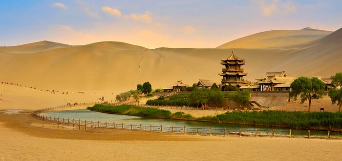 Ride a camel across the Singing Sand Dunes to get to Crescent Moon Spring