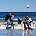 Dad and kids skating at a Bondi Beach ice rink during the Winter Festival