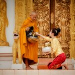 Woman giving a Buddhist monk an offering