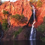 The setting sun turns the cliffs at Wangi Falls in Litchfield National Park a brilliant red