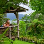 Happy mother and son relaxing on luxury villa veranda with tropical garden view during a Bali summer vacation