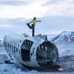 You'll stay warm with these tips, like this woman striking a yoga pose on top of the crashed plane at Sólheimasandur beach