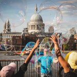 A street performer on the banks of the Thames with St Paul's Cathedral in the background