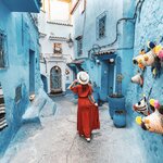 Young woman with red dress visiting the blue city Chefchaouen