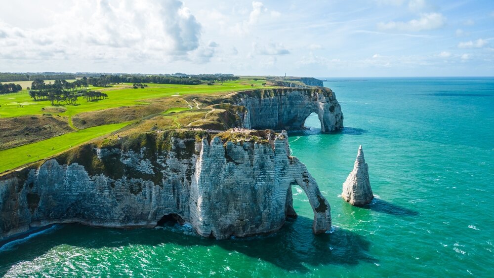 Aerial view of Etretat cliffs on the Normandy coast in France, with dramatic white chalk formations, natural arches, and the deep blue sea, a famous landmark for nature, travel, and adventure photo