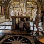 The hill on which Jesus was crucified, Golgotha is now mostly covered by years of older structures and erosion. Consequently, only the top of the hill where Jesus’ cross stood and the section just below, where there is a rift in the rock, and a side view of the rock are open for visitors.  These religious pilgrims have waited in a two-hour line to touch the hole in the top of the Golgotha rock where Jesus' cross was erected.  - Church of the Holy Sepulchre, Jerusalem, Israel | Photo taken by Rich W